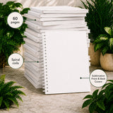 Stack of white notebooks with text labels on a neutral background with plants.