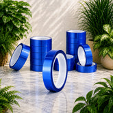 Blue rolls of tape on a marble surface with plants in the background