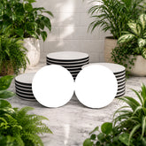 Set of black and white striped bowls on a marble surface with plants around