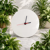 White wall clock with black and red hands on a marble surface surrounded by potted plants.