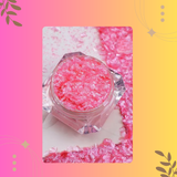 Pink glittery powder in a clear container on a colorful background