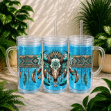 Three blue glittery tumblers with bull head design and straws on a stone surface with plants in the background.