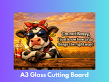 Cow with sunglasses and bandana sitting at a table with a drink, text 'I'm not bossy, I just know how to do things the right way!', and 'A3 Glass Cutting Board' text on a colorful background.