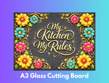Decorative glass cutting board with floral designs and 'My Kitchen My Rules' text on a gradient background.