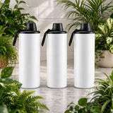 Three white insulated bottles with black lids on a wooden surface surrounded by plants.
