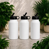 Three white insulated bottles with black lids on a stone surface surrounded by plants.