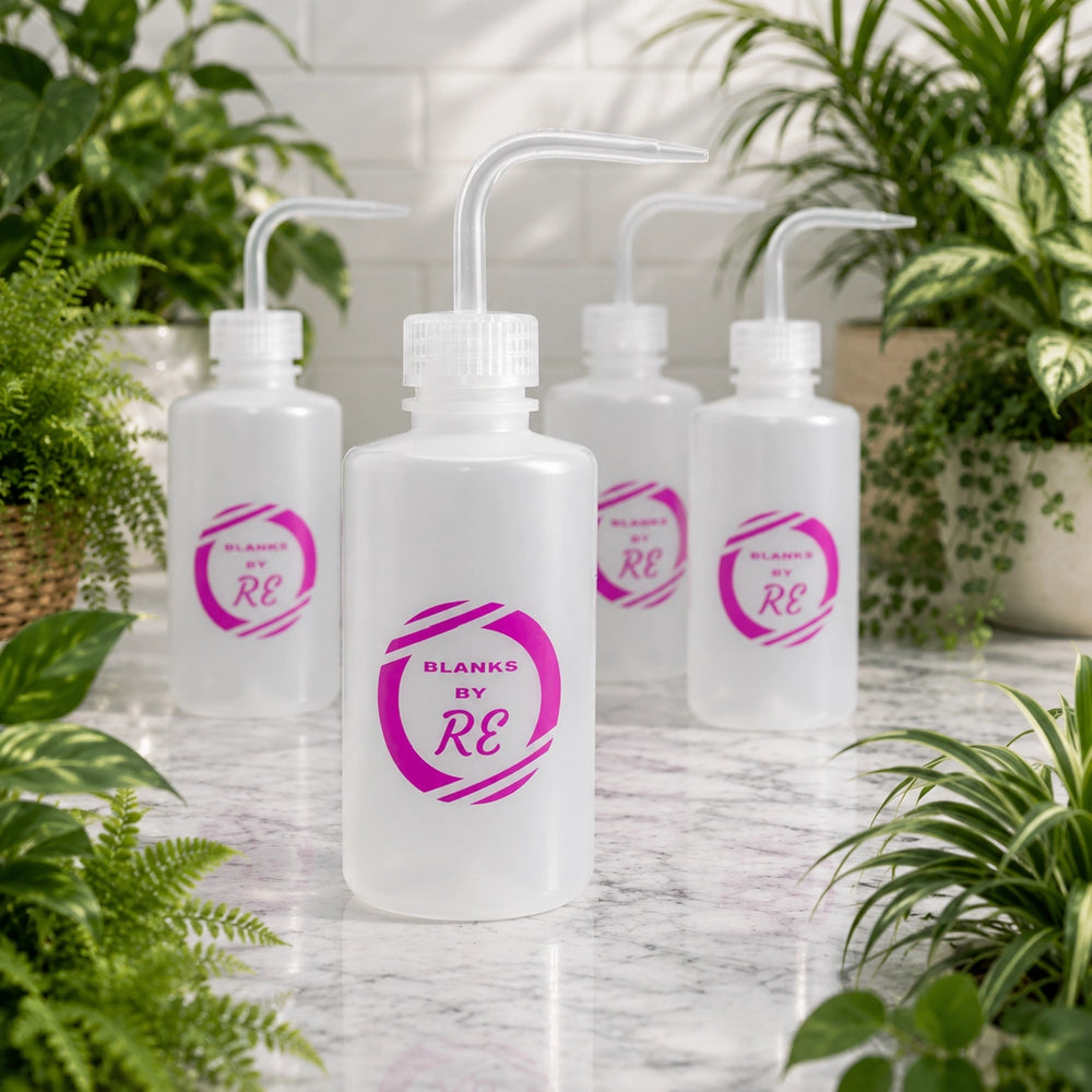 Four white bottles with 'Blanks by RE' logo on a marble surface surrounded by plants.
