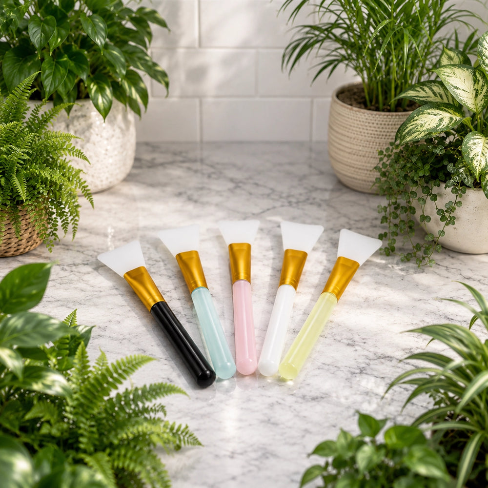 Set of plant cleaning brushes with colorful handles on a marble surface surrounded by potted plants.