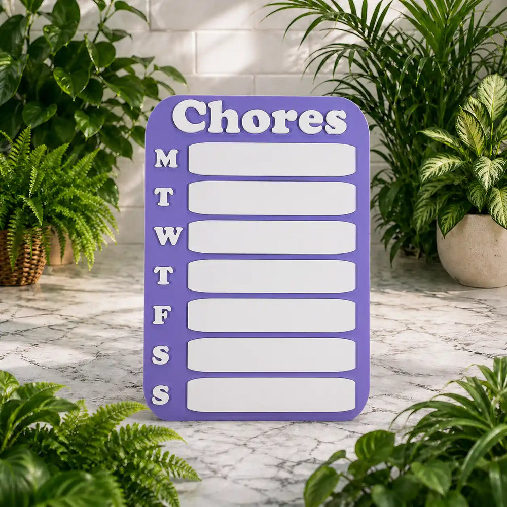 Purple chore chart with days of the week on a marble surface surrounded by plants