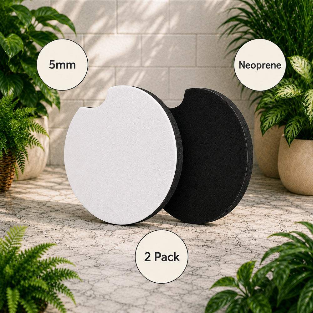 Two round black and white coasters with text labels on a stone surface with plants.