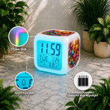 Colorful digital clock with 7 color shift feature, alarm function, and battery operation on a stone surface with plants.