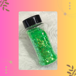 Bottle of green glitter with a black lid on a textured white surface.