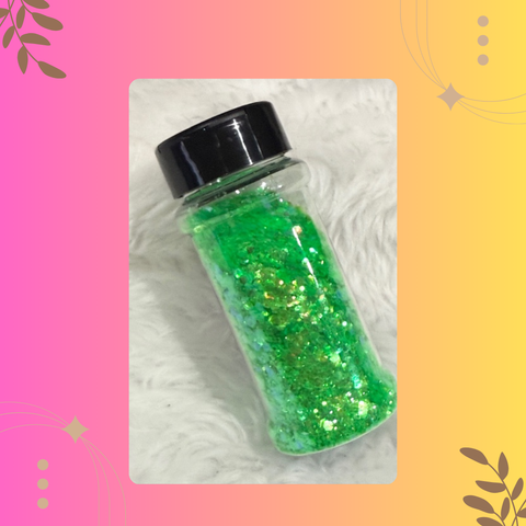 Bottle of green glitter with a black lid on a textured white surface.