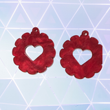 Red heart-shaped earrings on a geometric blue background