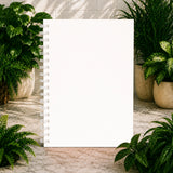 White spiral-bound notebook with plants on a marble surface