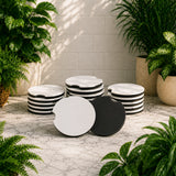 Set of black and white striped stools on a stone patio with plants around.