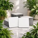 White and black striped cube-shaped ottomans on a marble floor with plants around.