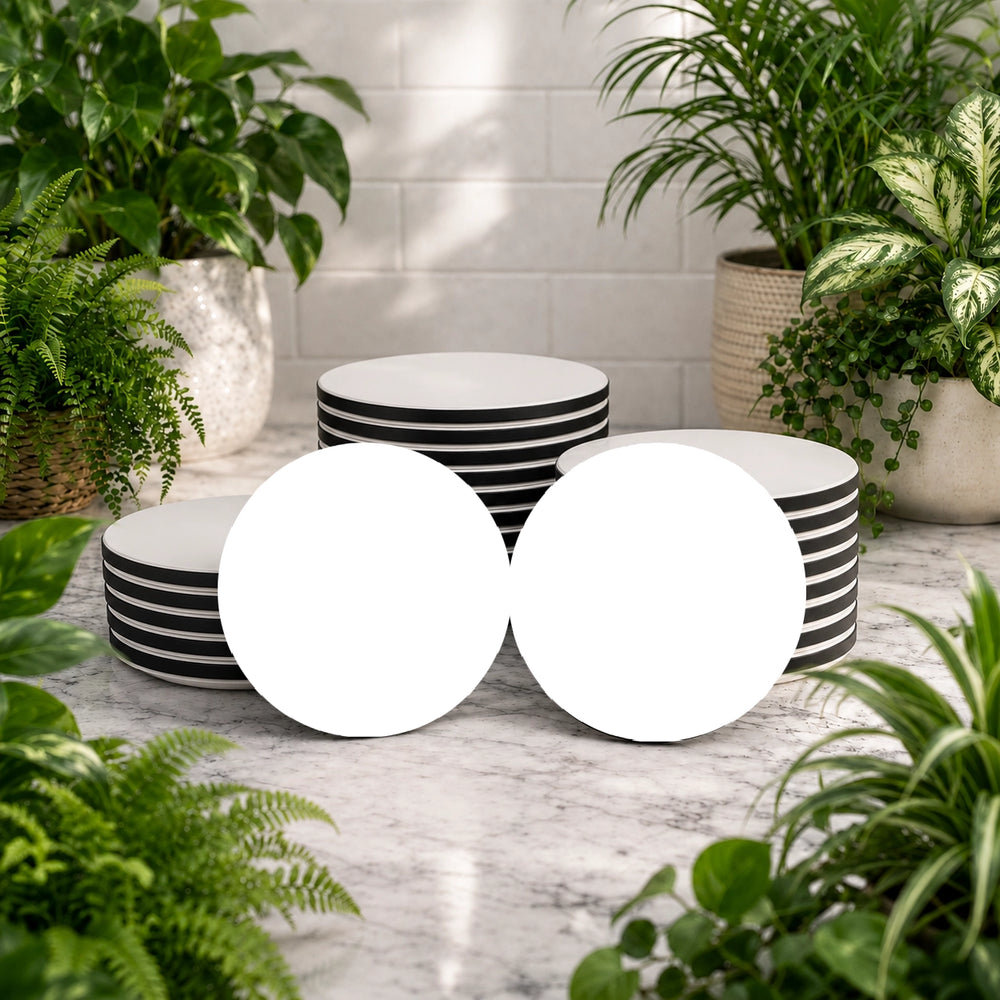 Set of black and white striped bowls on a marble surface with plants around