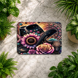 Decorative mat with floral and snake design on a textured surface surrounded by plants