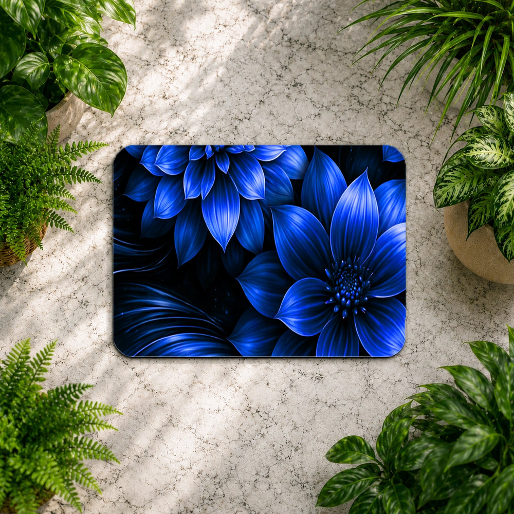 Blue floral design on a rectangular mat surrounded by green plants on a stone surface