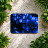 Blue floral design on a rectangular mat surrounded by green plants on a stone surface