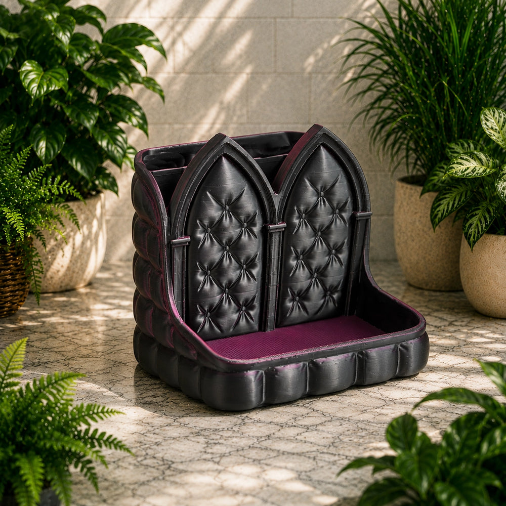 Black tufted cushion with purple interior on a stone floor surrounded by plants