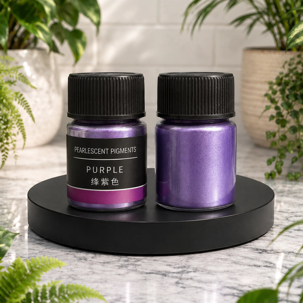Two containers of purple pearlescent pigments on a black stand with plants in the background.
