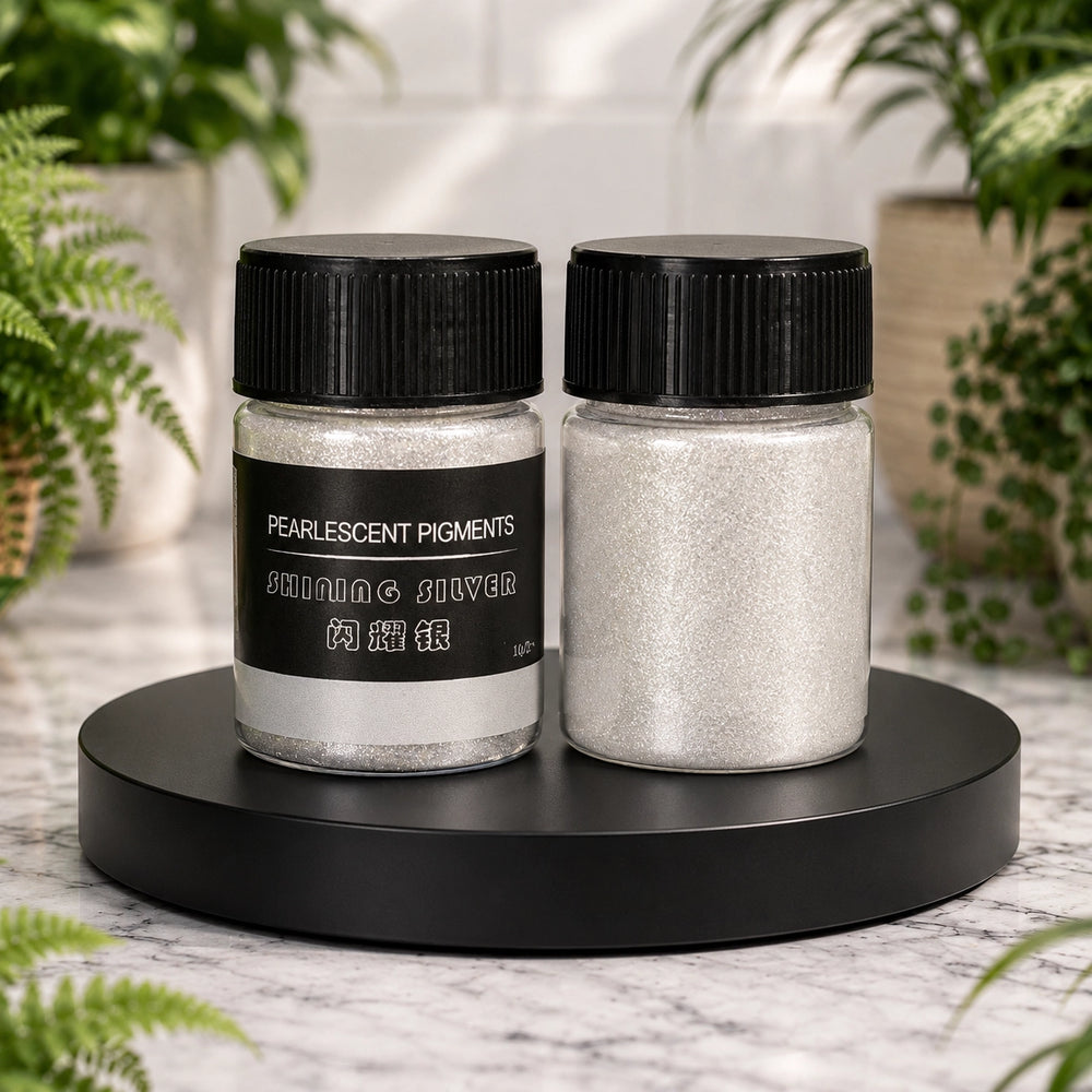 Two jars of pearlescent pigments on a black stand with plants in the background
