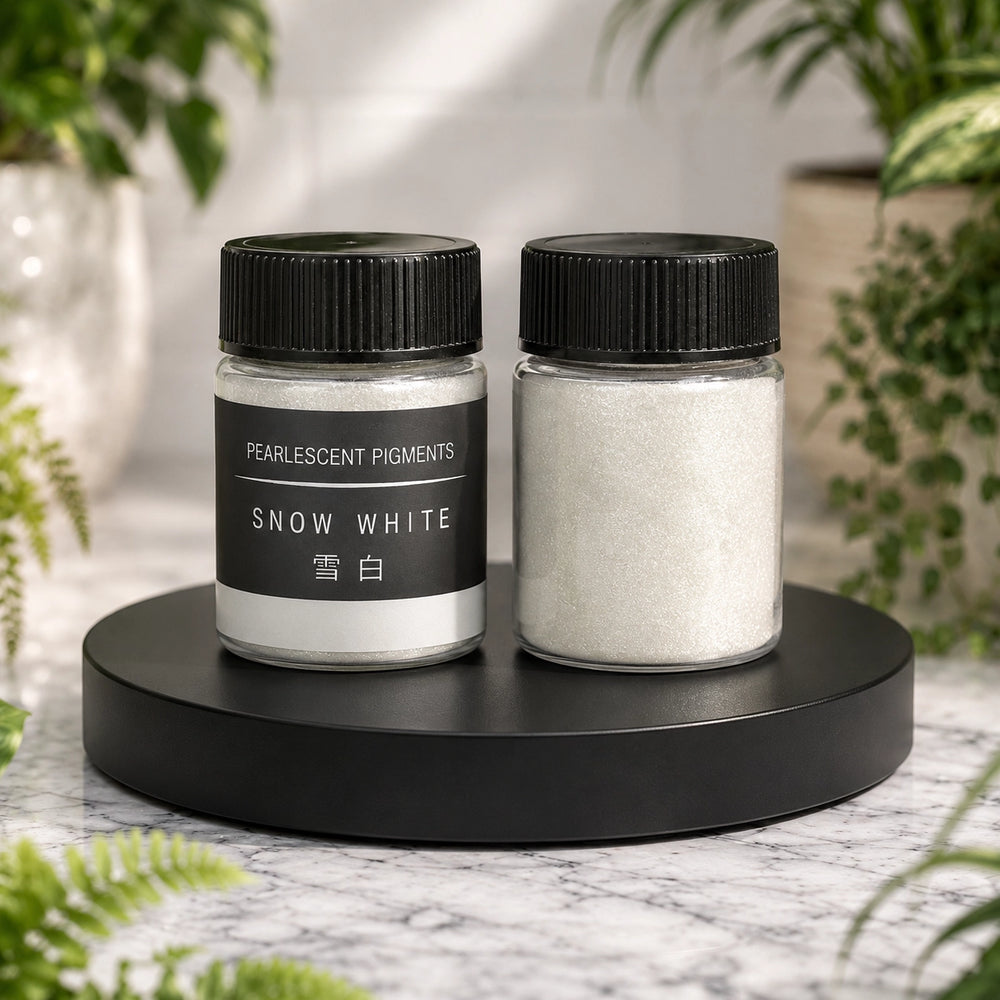 Two jars of pearlescent pigments labeled 'Snow White' on a black stand with a blurred natural background.