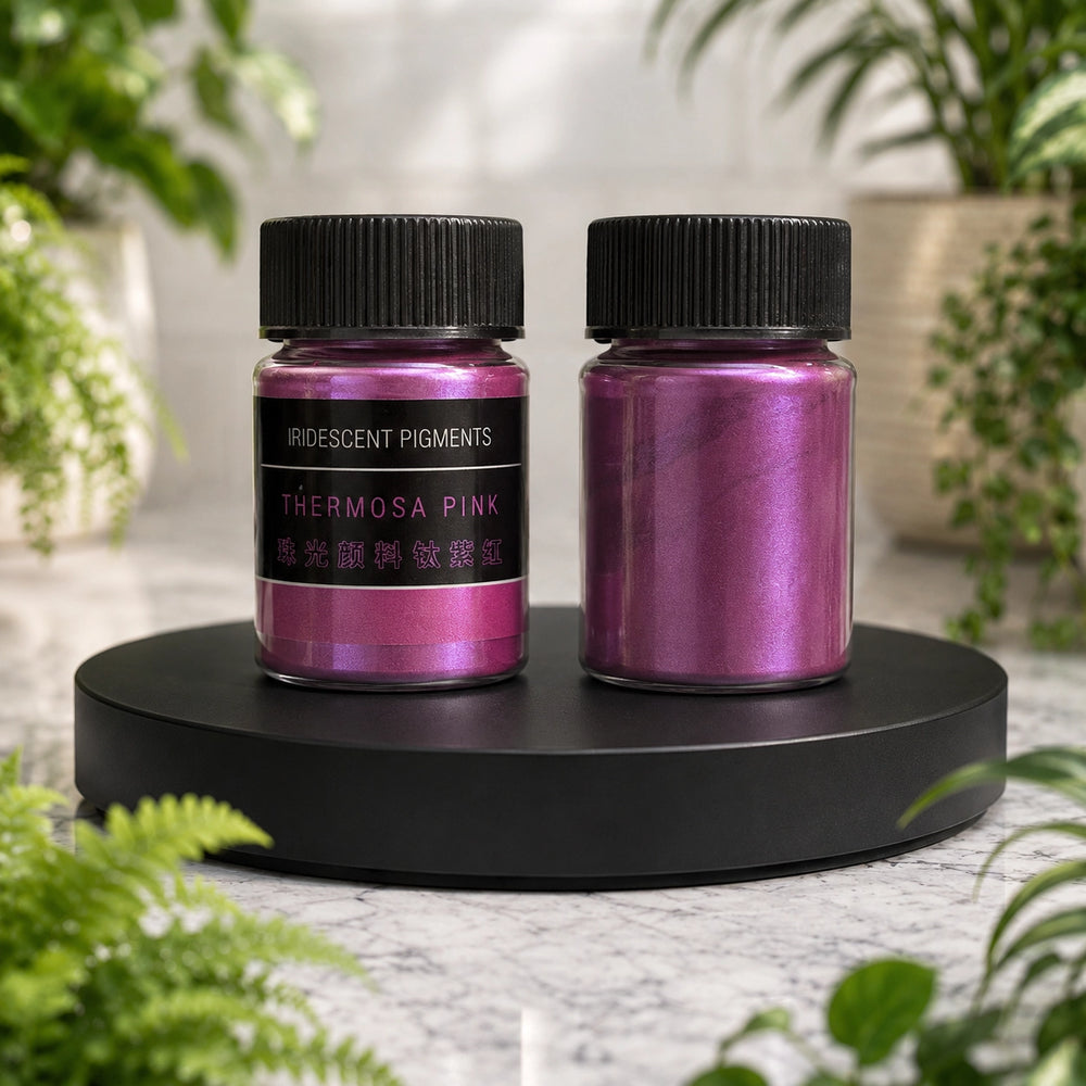 Two bottles of thermosha pink pigment on a black stand with a blurred greenery background