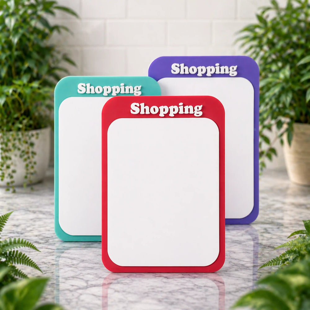 Three colorful magnetic dry erase boards on a marble surface with plants in the background.