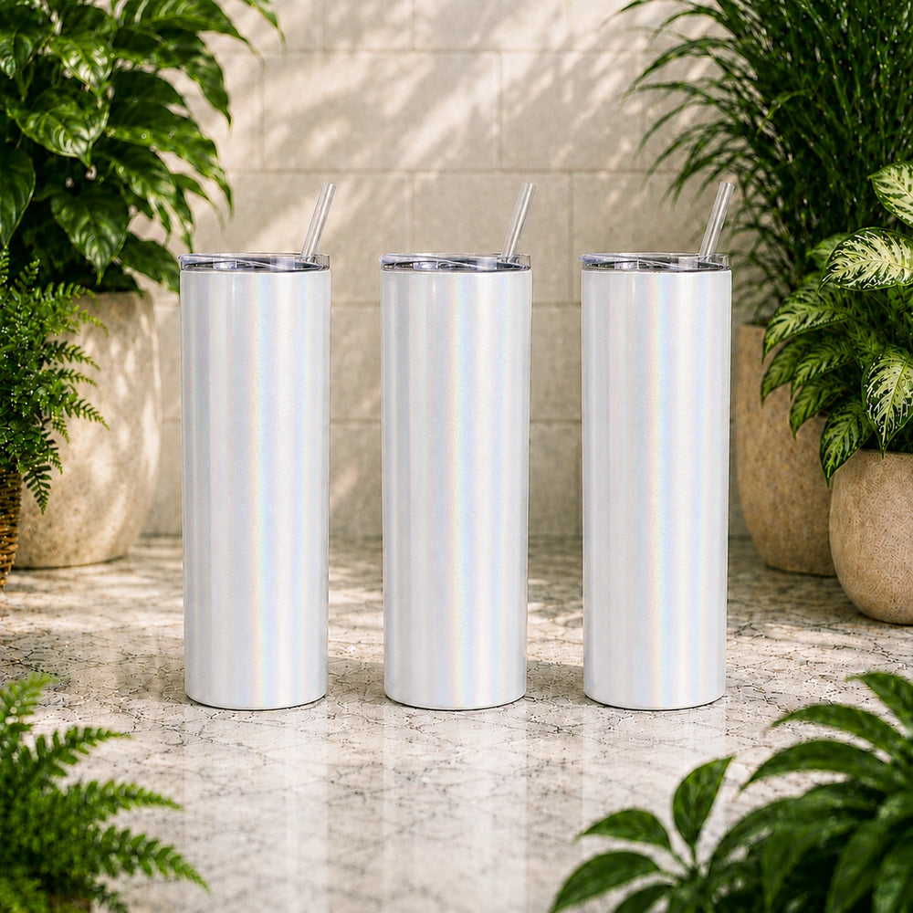Three white tumblers with straws on a stone surface surrounded by plants
