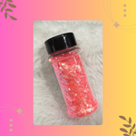 Bottle of red glitter with a black lid on a textured surface with decorative elements.