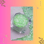 Green glittery substance in a clear container on a colorful background