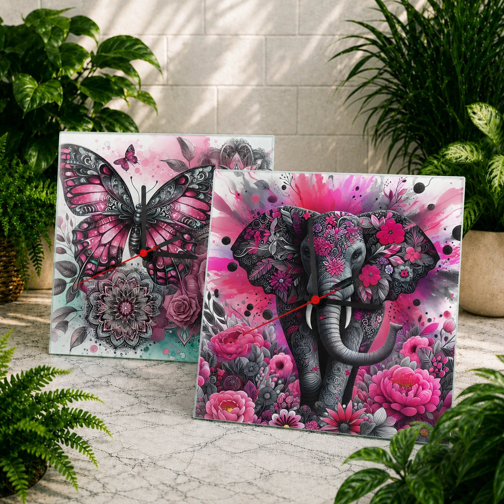 Two decorative wall clocks with butterfly and elephant designs on a marble surface with plants in the background.