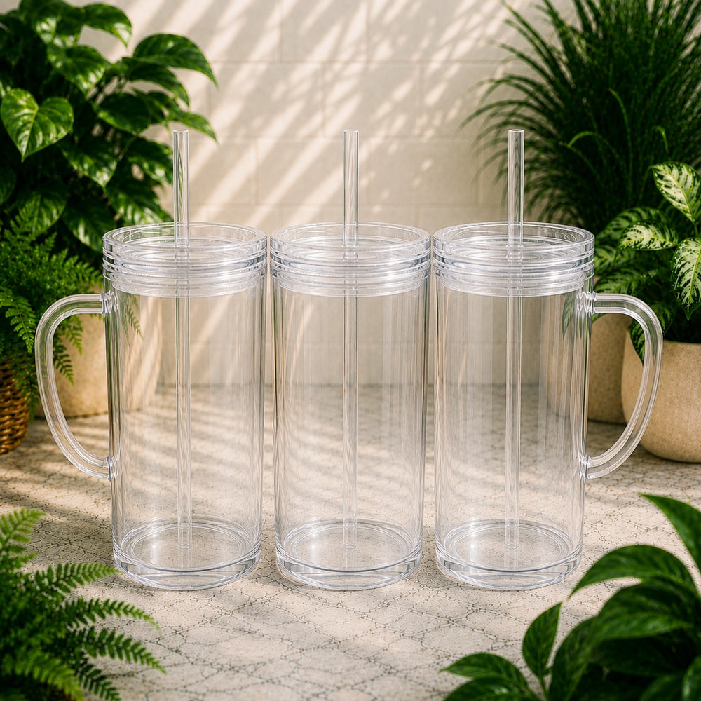 Three clear plastic tumblers with handles and straws on a stone surface with plants in the background.